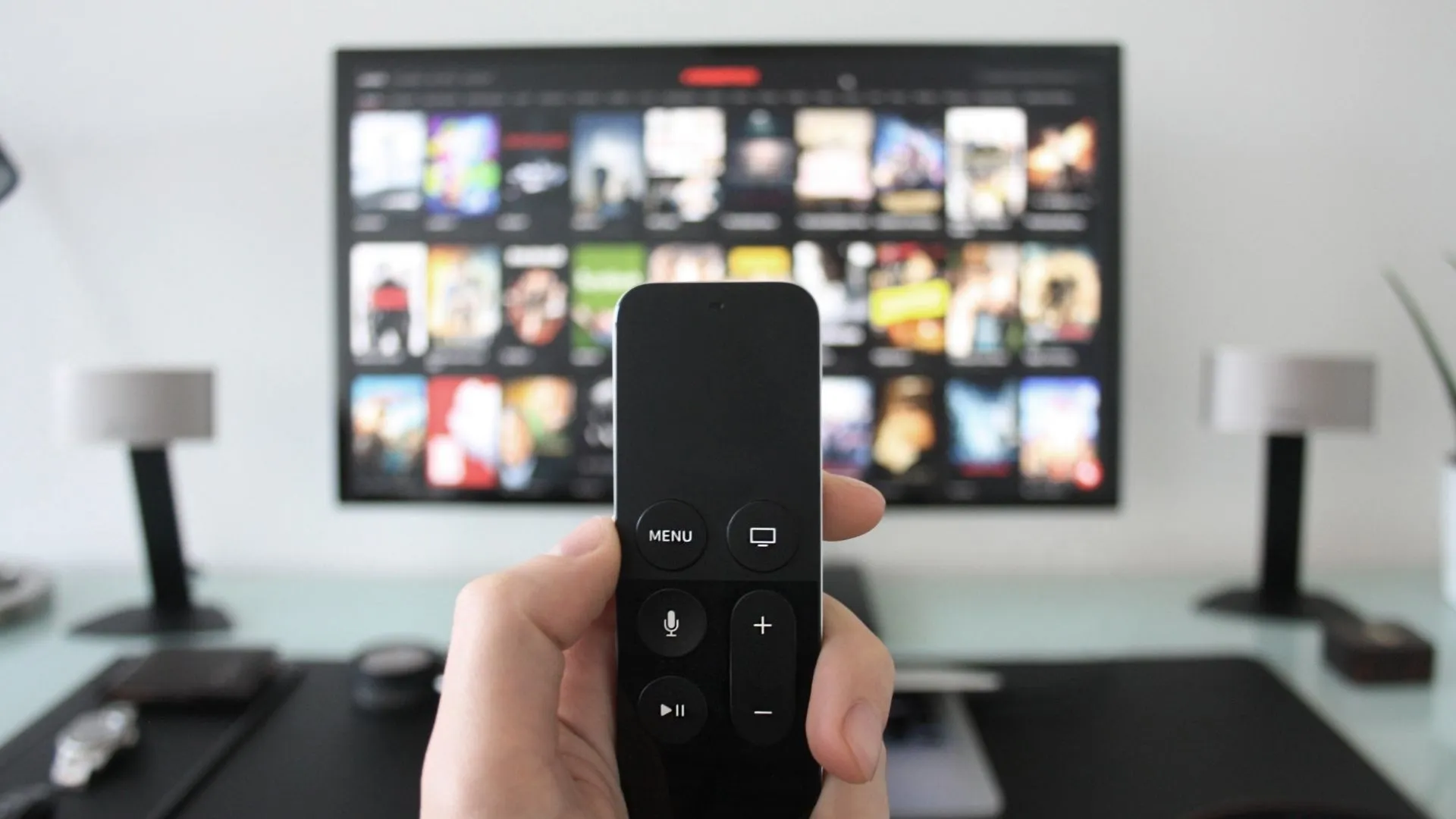 Persona con control remoto apuntando hacia una pantalla de televisión con múltiples películas de química y ciencia.