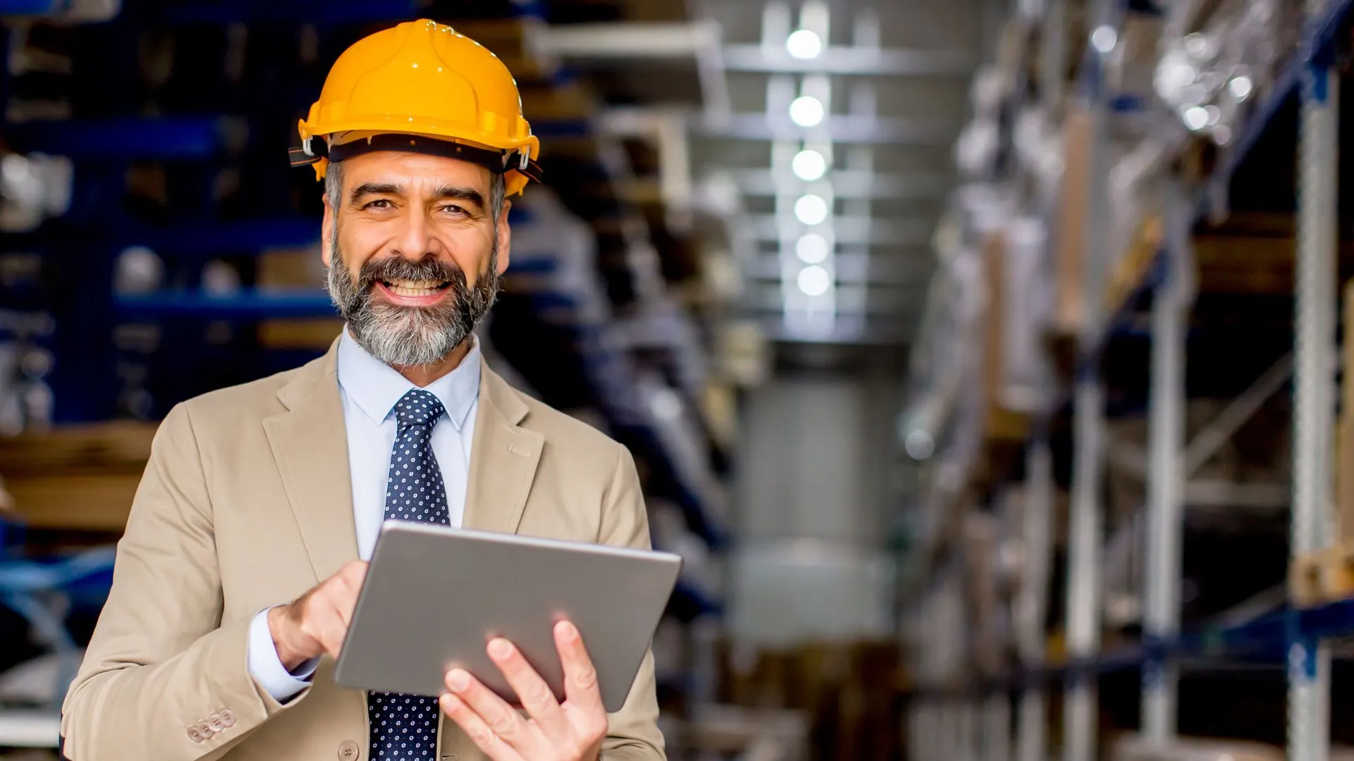 Hombre con casco de seguridad usando una tablet dentro de un almacén industrial, representando el uso de un buscador inteligente de productos químicos para tomar decisiones técnicas.